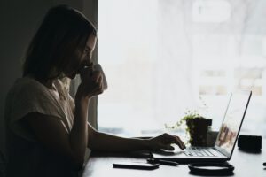 Dame drinkt koffie achter laptop op bureau